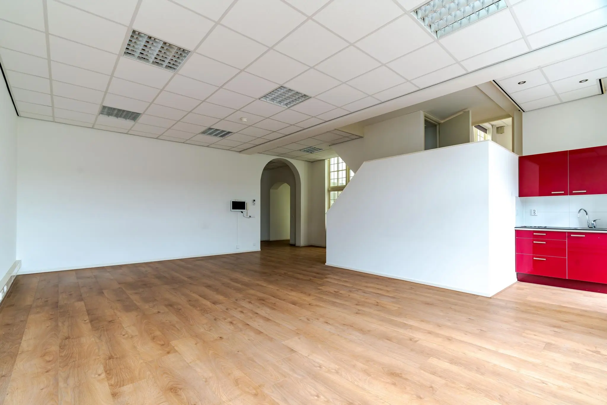 Lichte, lege kantoorruimte aan het Lange Voorhout met houten vloer, systeemplafond en rode kitchenette.